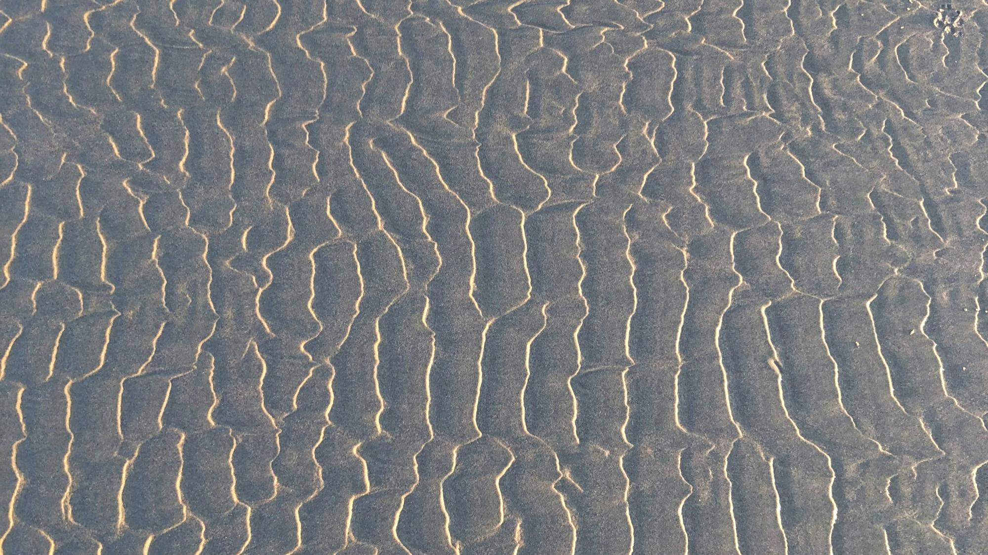 Beach sand rippled into a pattern by water.